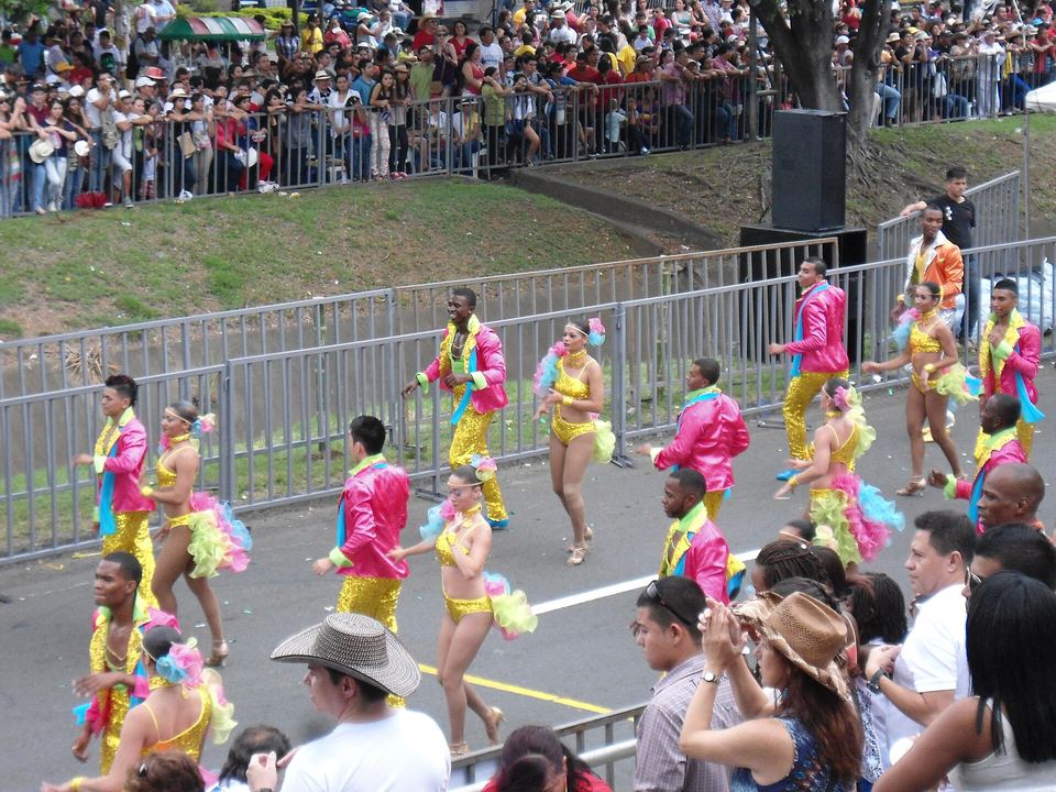 Bailarines con trajes de colores desfilando en el Salsódromo de la Feria de Cali, ante el público
