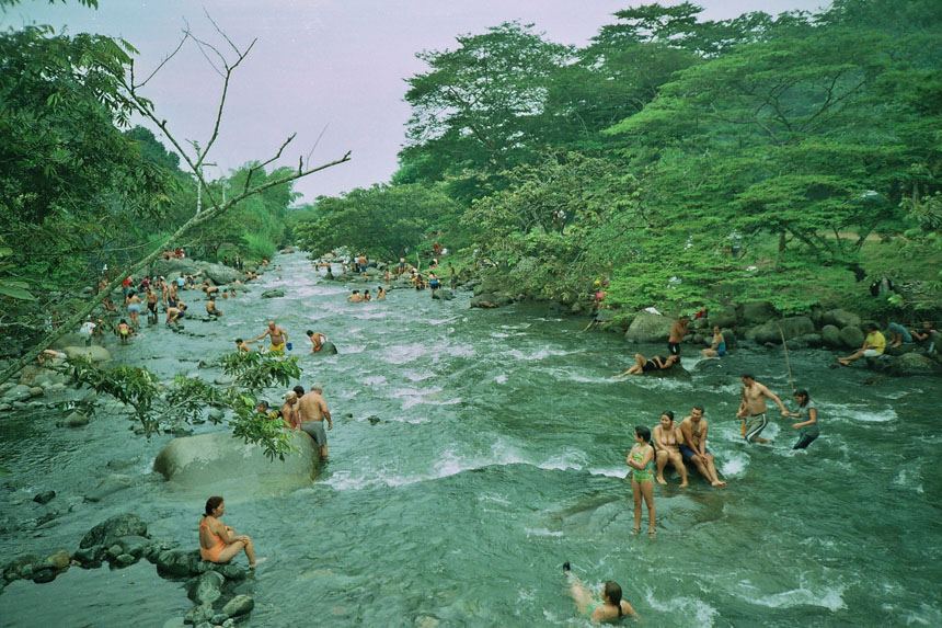 Bañistas en las aguas del río Pance, rodeado de árboles, en un domingo de paseo
